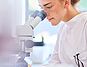 Frau sitzt vor einem Mikroskop | Protefix