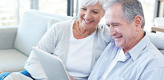 Älteres Paar sitzt vor einem Tablet